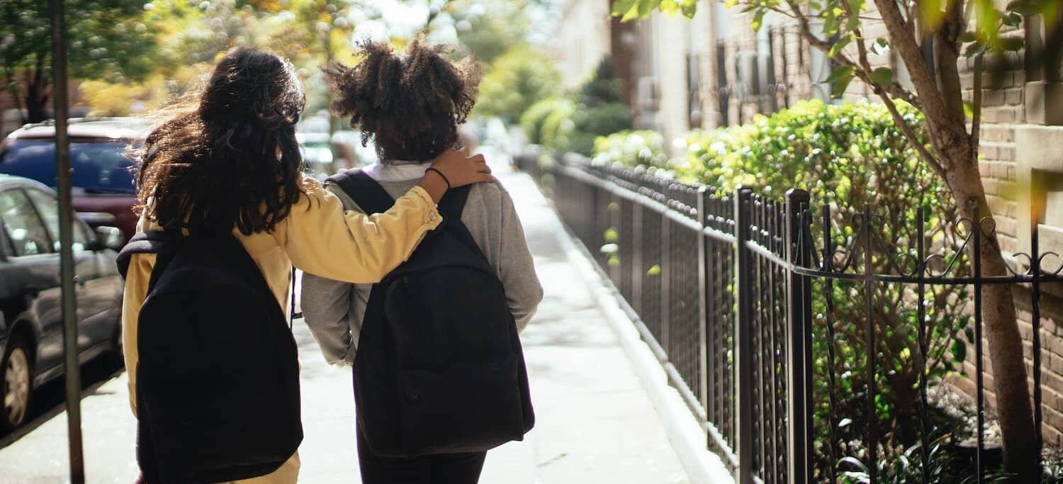 Two friends walking with one arm around the other