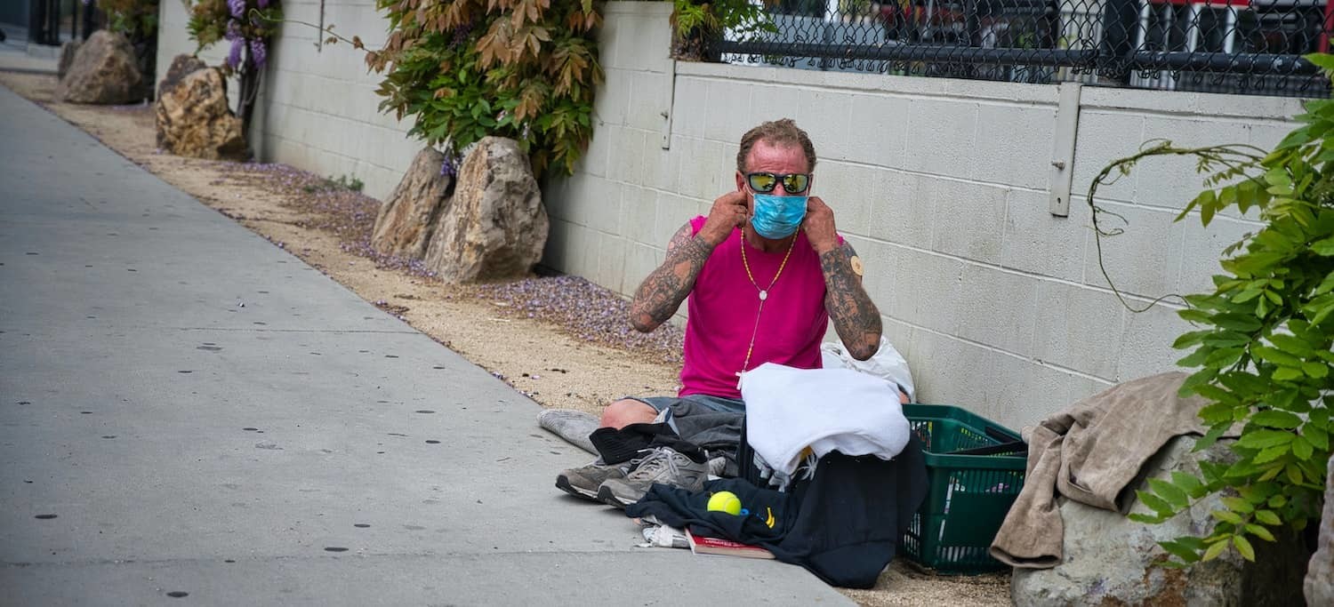 A Homeless Person Puts on a Face Mask During the COVID-19 Pandemic