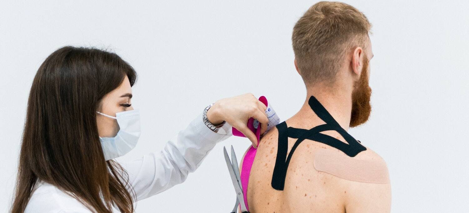 Doctor kinesiology taping patient to reduce pain