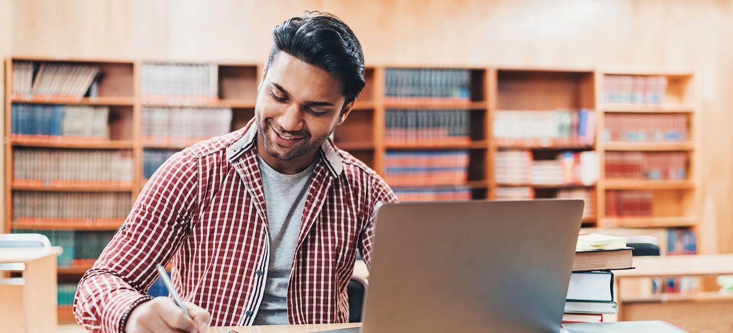 Man in a Public Library Earning a Postgraduate Dentistry Degree Online