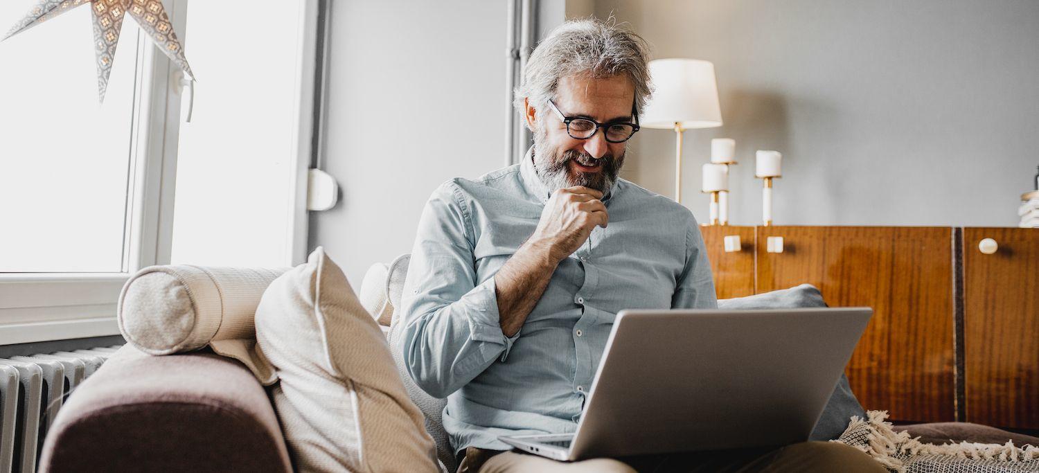 Older Man Studying for an Online Postgraduate Degree in Orofacial Pain and Oral Medicine on his Laptop at Home