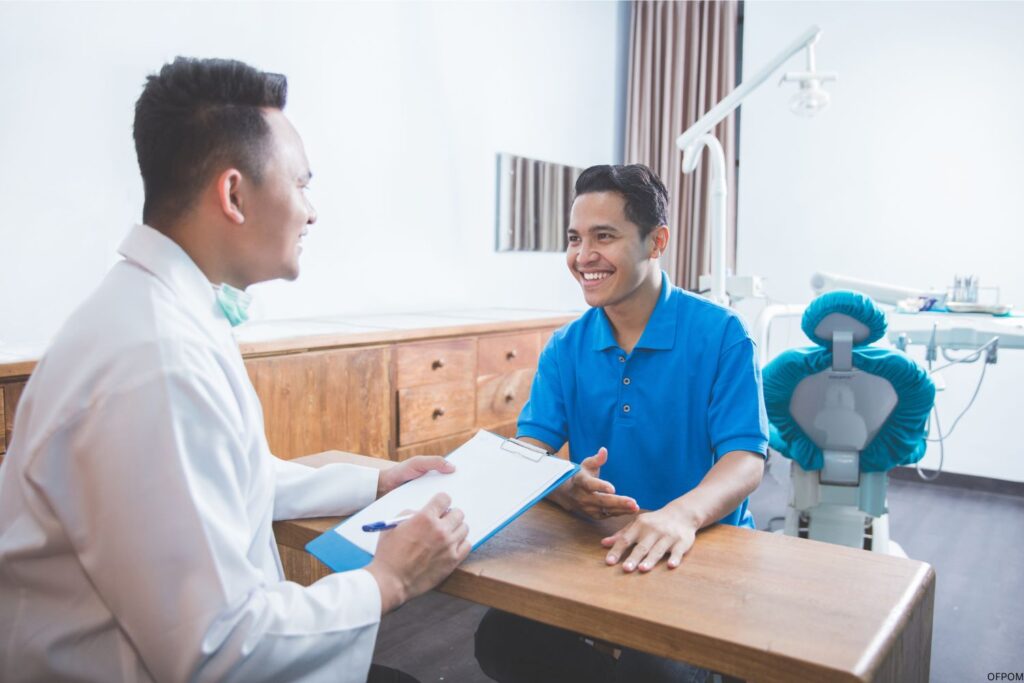 Dentist sitting with patient at a desk with a checklist.