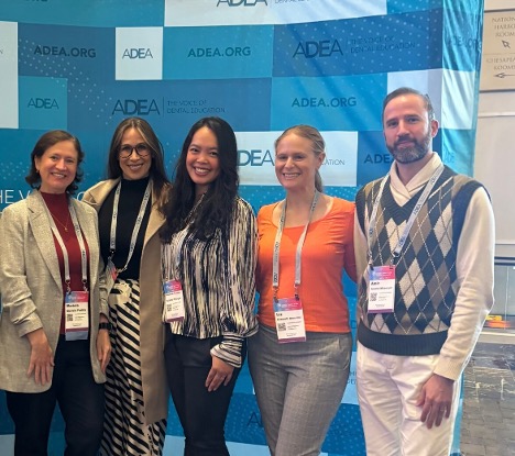 Community Oral Health faculty members smiling in front of an ADEA banner.